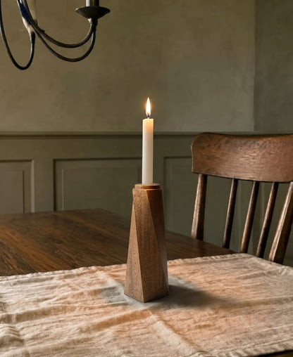 Portavelas Tornado encendido sobre una mesa de comedor de madera, con la pared en verde oliva al fondo