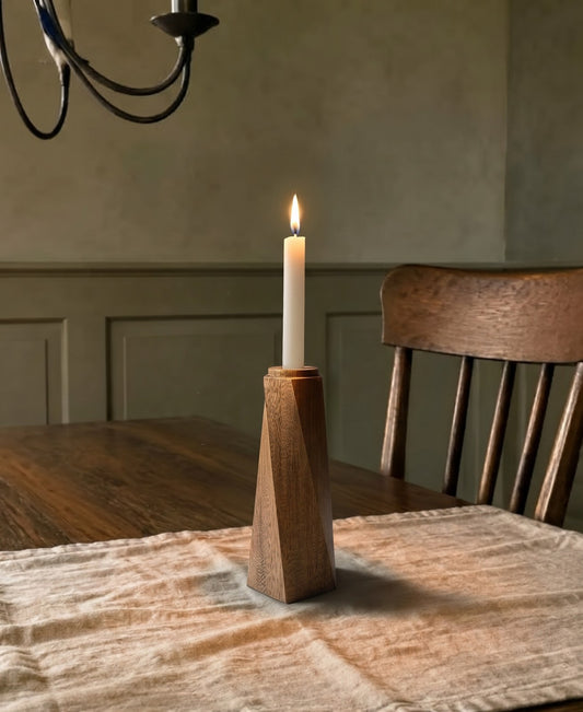 Portavelas Tornado encendido sobre una mesa de comedor de madera, con la pared en verde oliva al fondo